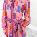 Person wearing a colorful pink dress with abstract patterns on a white background