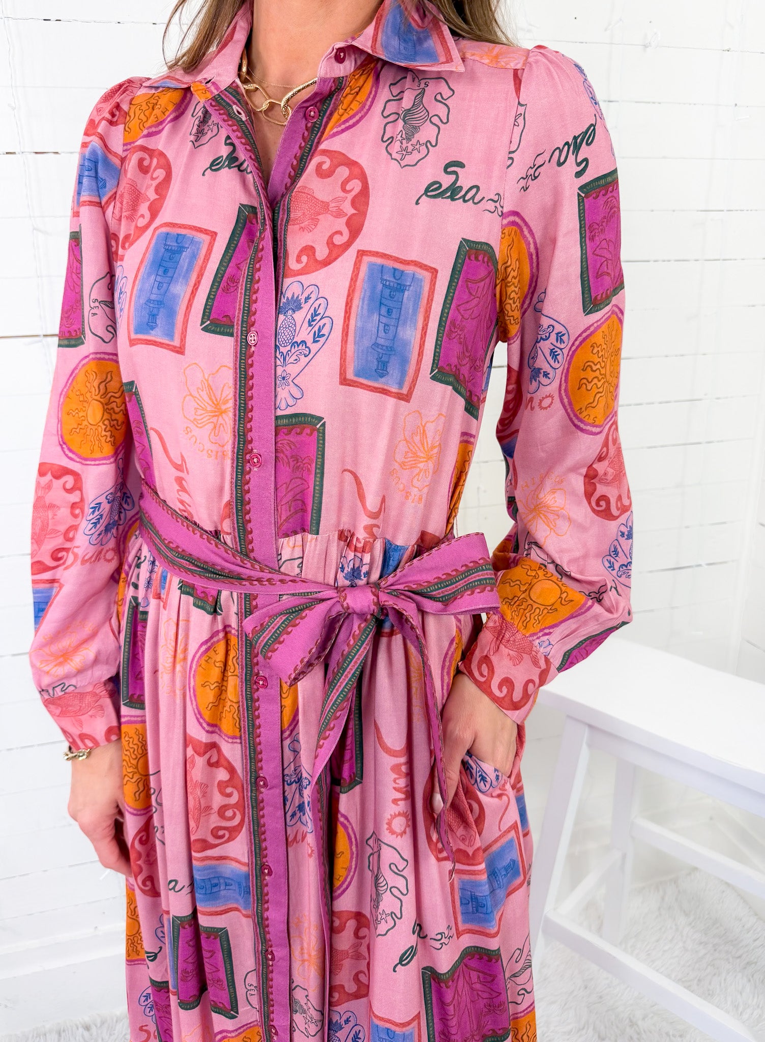 Person wearing a colorful pink dress with abstract patterns on a white background