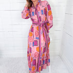 Woman wearing a colorful dress with geometric pattern against a white wooden panel background