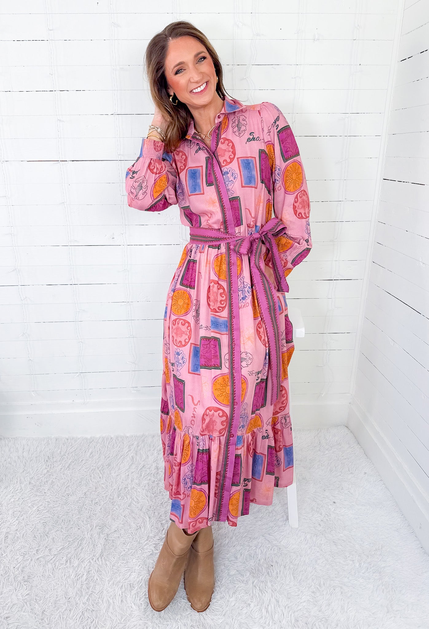 Woman wearing a colorful dress with geometric pattern against a white wooden panel background