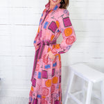 Woman wearing a colorful patterned dress against a white wooden panel background
