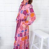 Woman wearing a colorful patterned dress against a white wooden panel background
