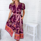 Woman wearing a patterned dress standing against a white wooden panel background