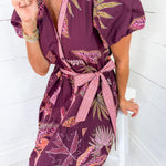 Woman wearing a purple floral dress with a white background