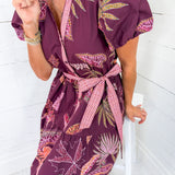 Woman wearing a purple floral dress with a white background