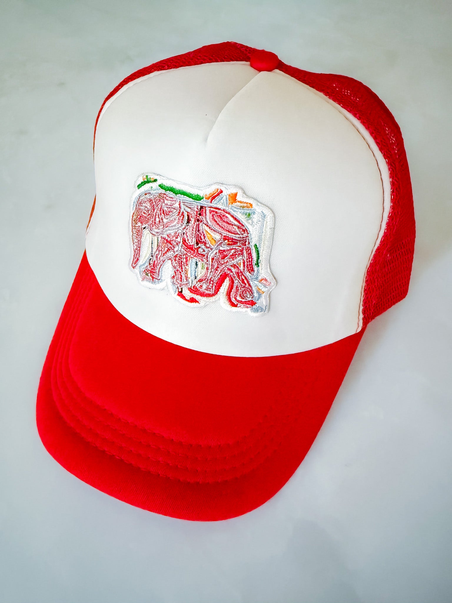 Red and white cap with an embroidered elephant design on a light gray background