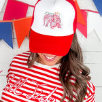 Person wearing a red and white cap with an elephant design and a red and white striped shirt with text.