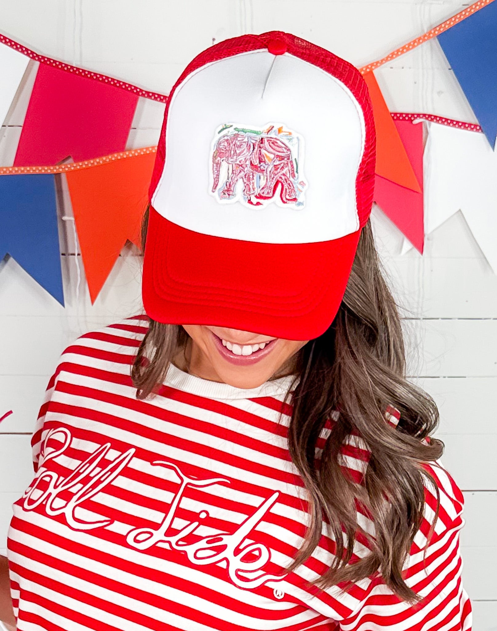 Person wearing a red and white cap with an elephant design and a red and white striped shirt with text.