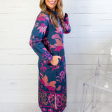 Woman wearing a blue and pink patterned dress against a white wooden panel background