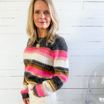 Woman wearing a colorful striped sweater against a white wooden panel background