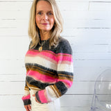 Woman wearing a colorful striped sweater against a white wooden panel background