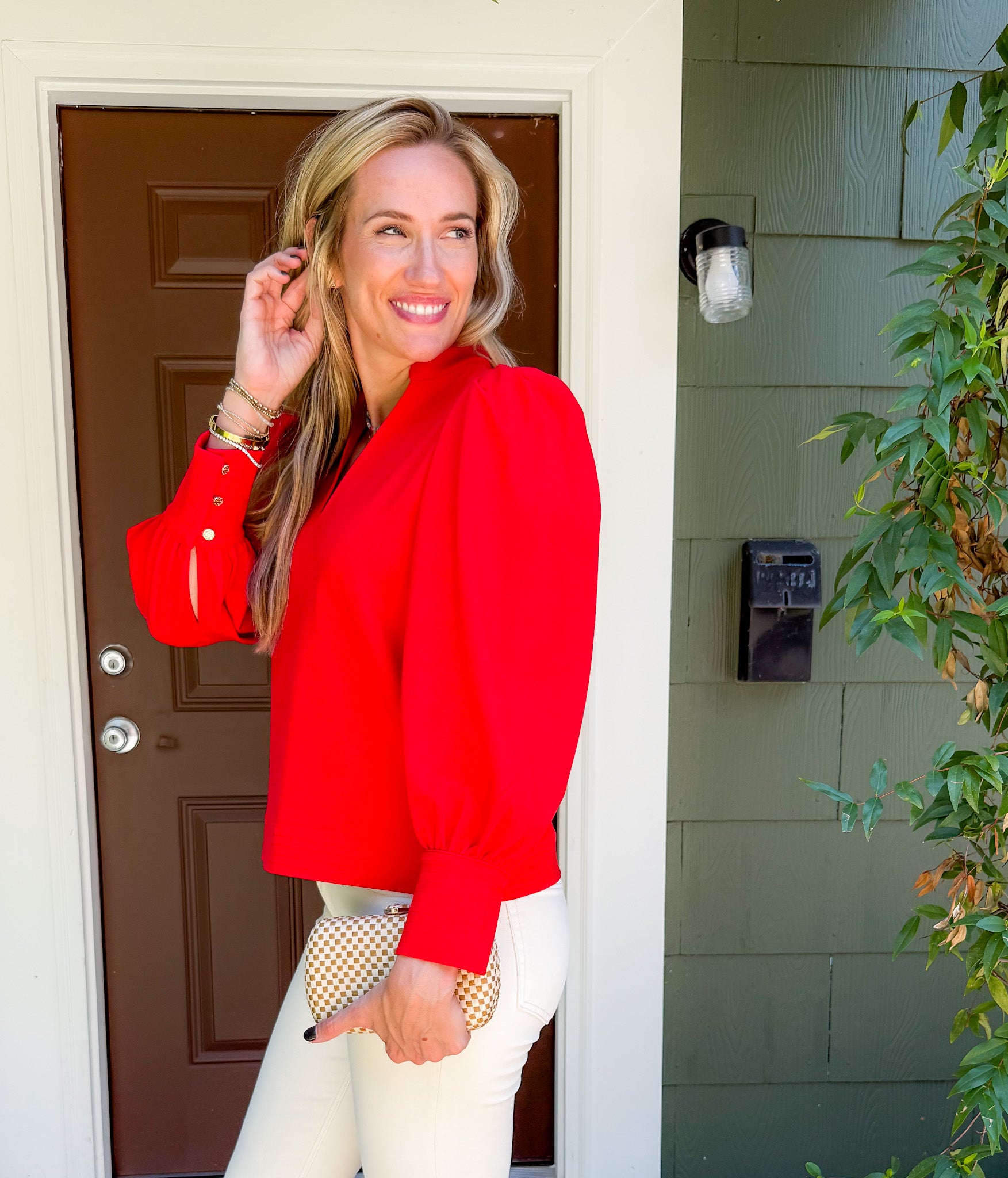 Woman in a red jacket standing outside a house