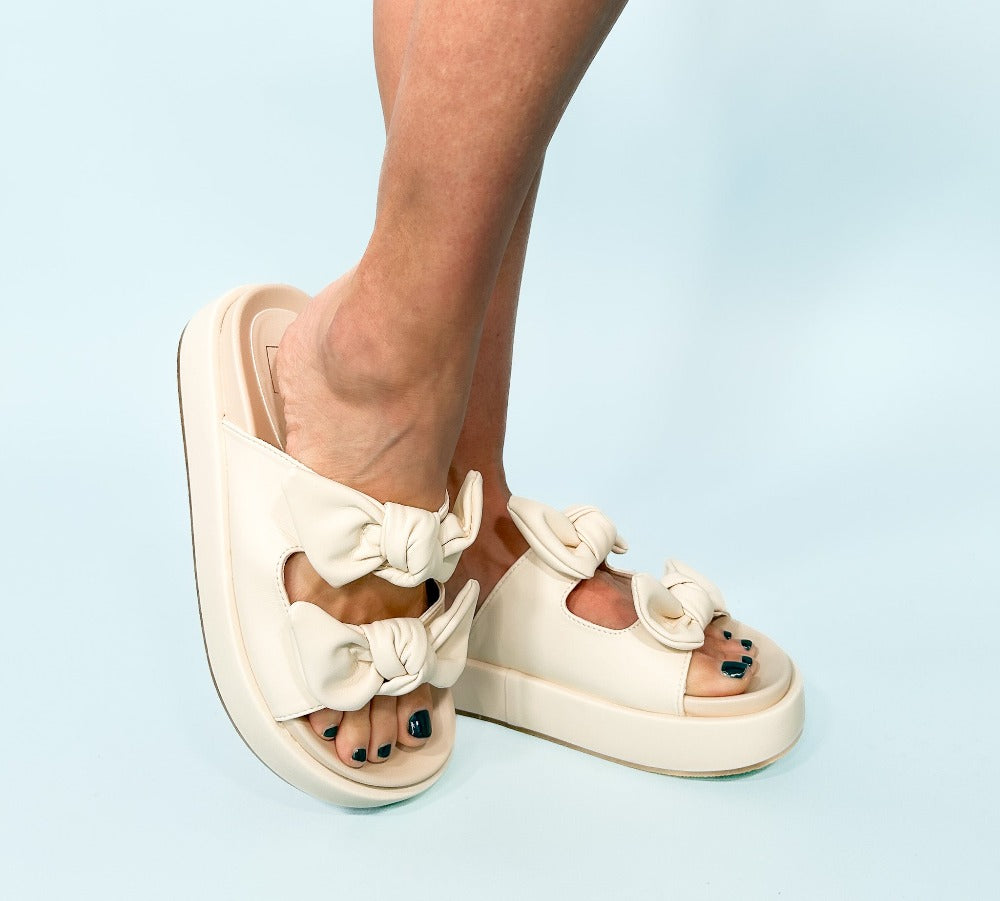 model wearing white sandals with bows