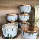 Set of small ceramic containers with gold lids on a textured surface