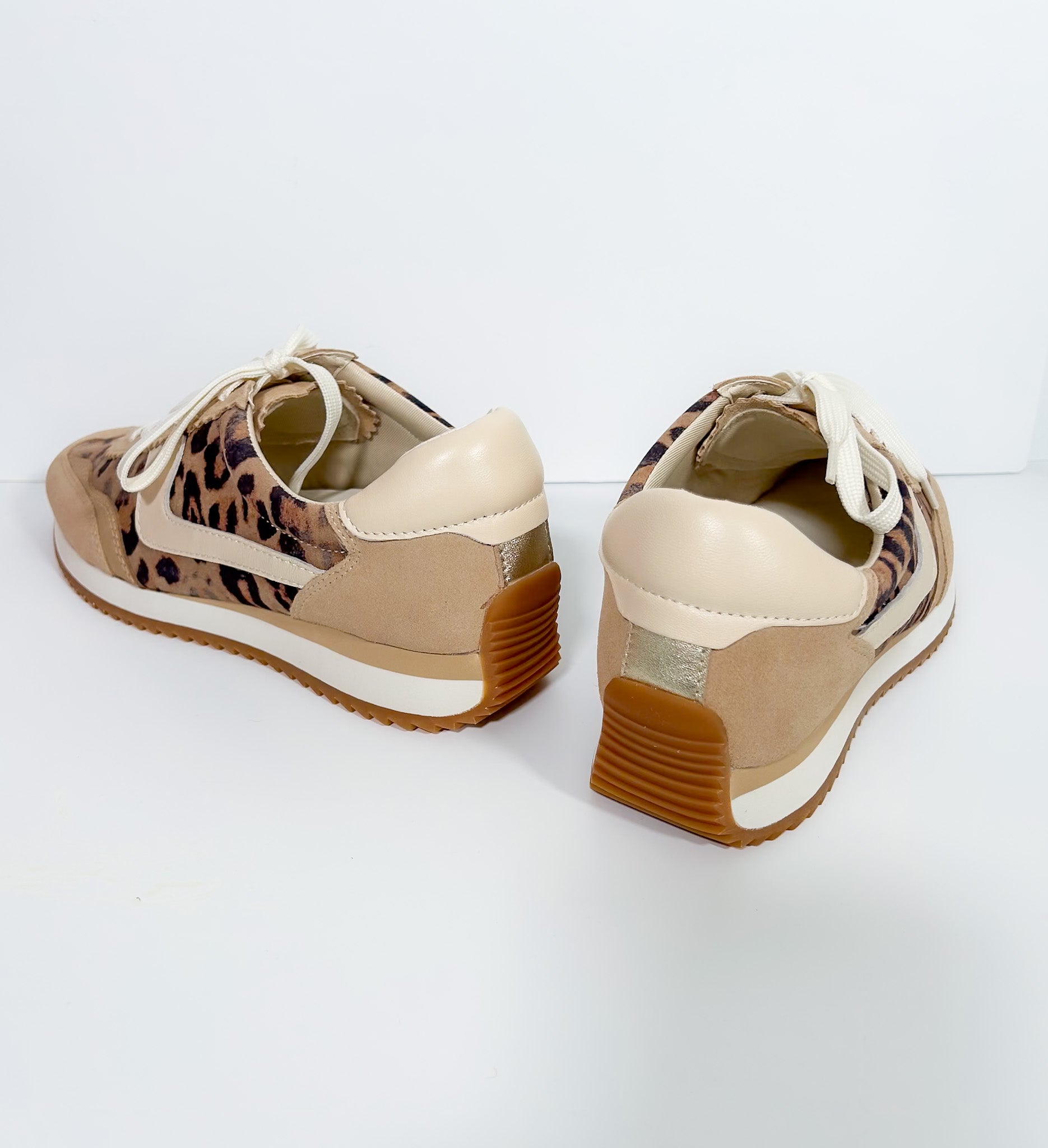 Pair of beige sneakers with leopard print accents on a white background