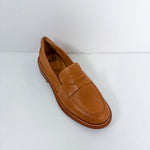 A single tan leather penny loafer shoe photographed from an elevated angle on a plain white background.