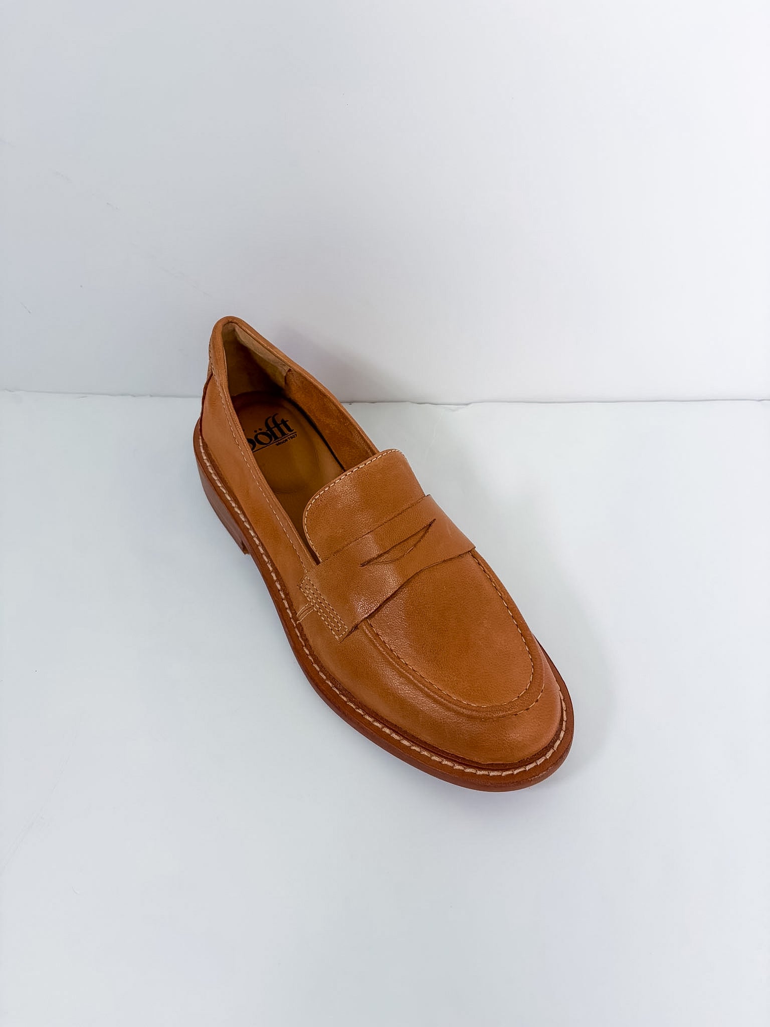 A single tan leather penny loafer shoe photographed from an elevated angle on a plain white background.