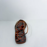 A single flat thong sandal in a glossy tortoiseshell pattern, featuring a small gold-tone metal brand plaque on the toe bed. The brand name 'SARABINO' is clearly visible on the plaque.