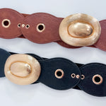 Two leather belts with gold oval buckles on a light gray background