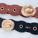 Two leather belts with gold oval buckles on a light gray background