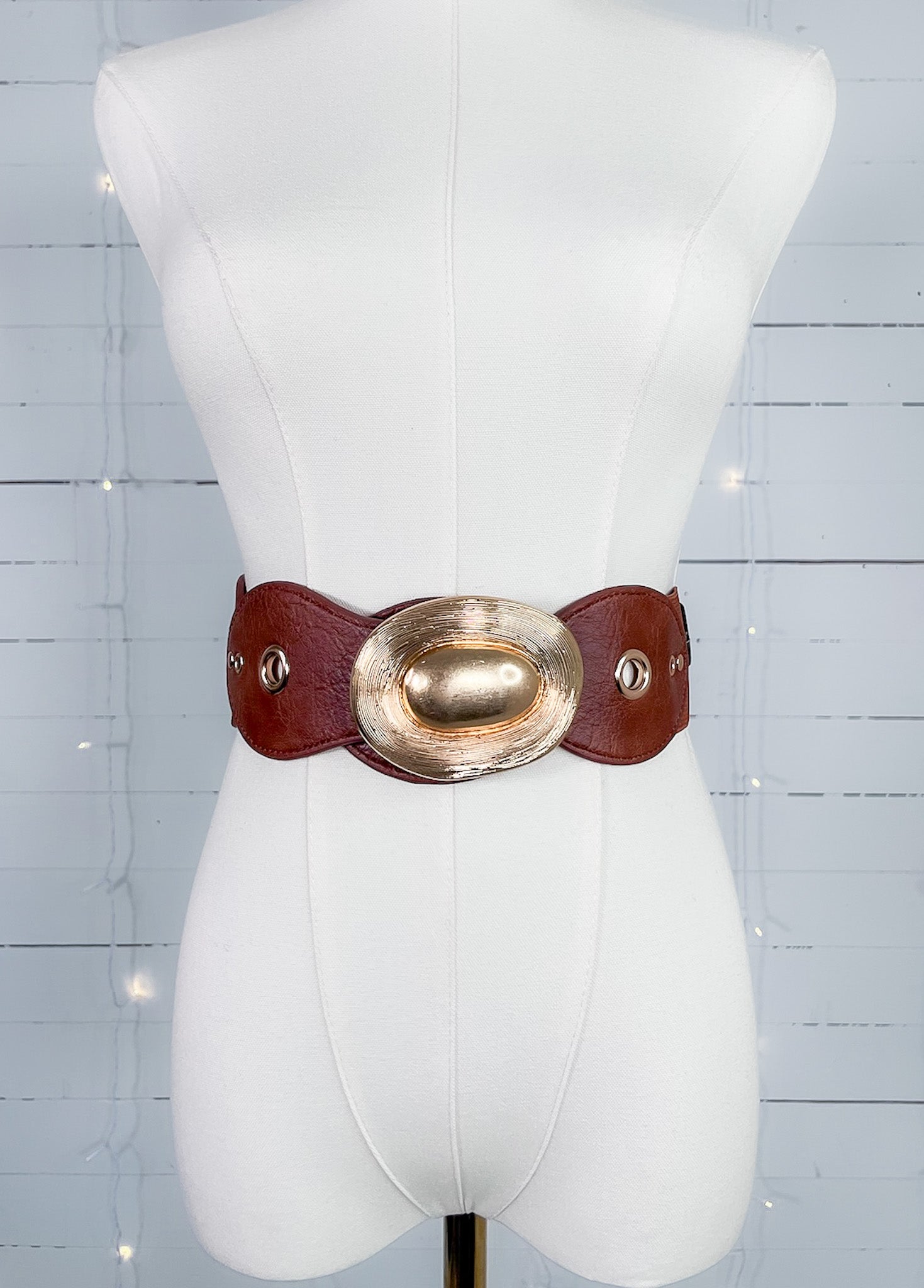 Mannequin wearing a wide leather belt with a gold buckle on a light blue background
