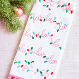Decorative towel with 'fa la la' text and Christmas lights design on a white background.