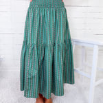 Person wearing a green patterned skirt with a white background