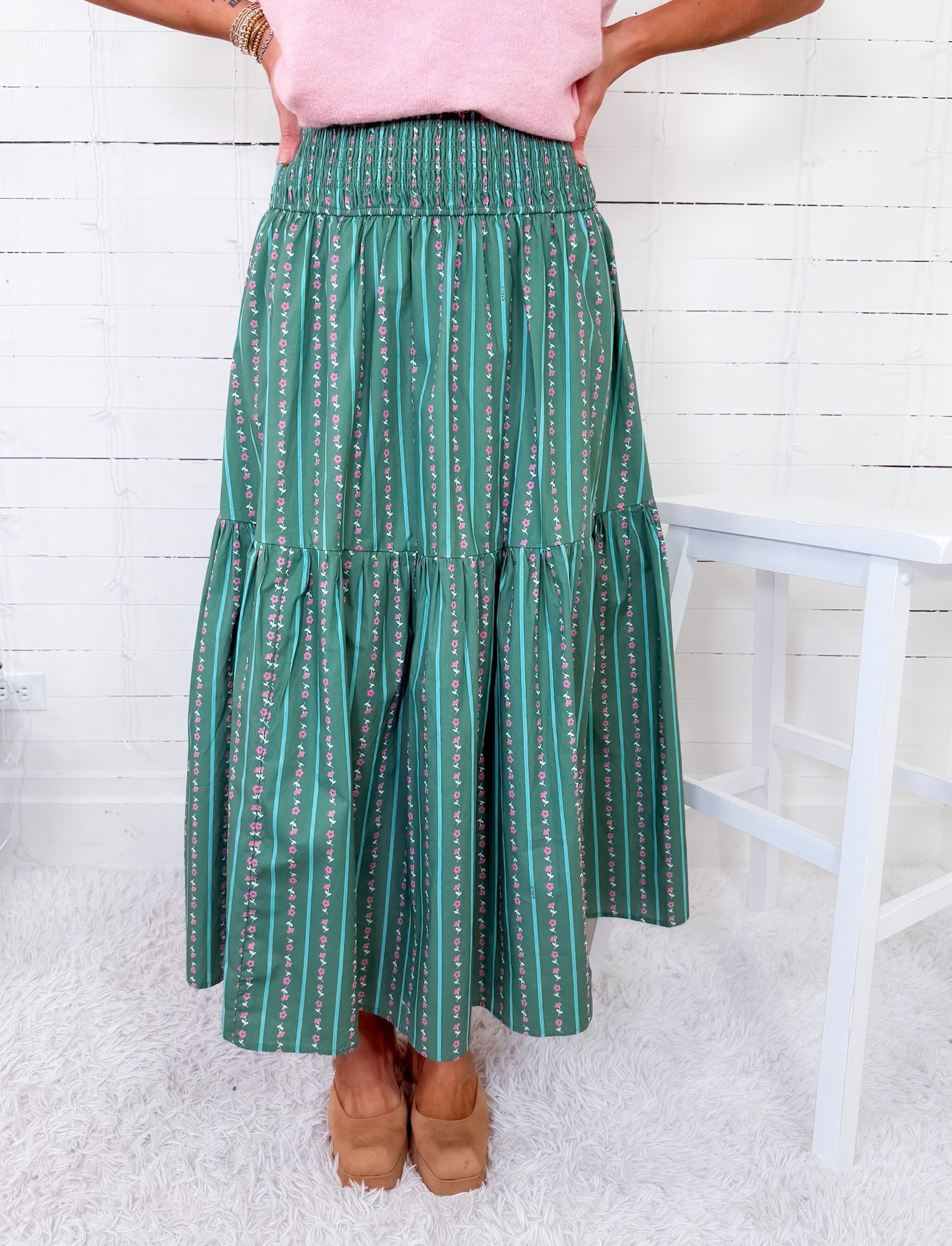 Person wearing a green patterned skirt with a white background