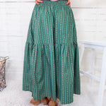 Person wearing a green patterned skirt with a white wooden floor background