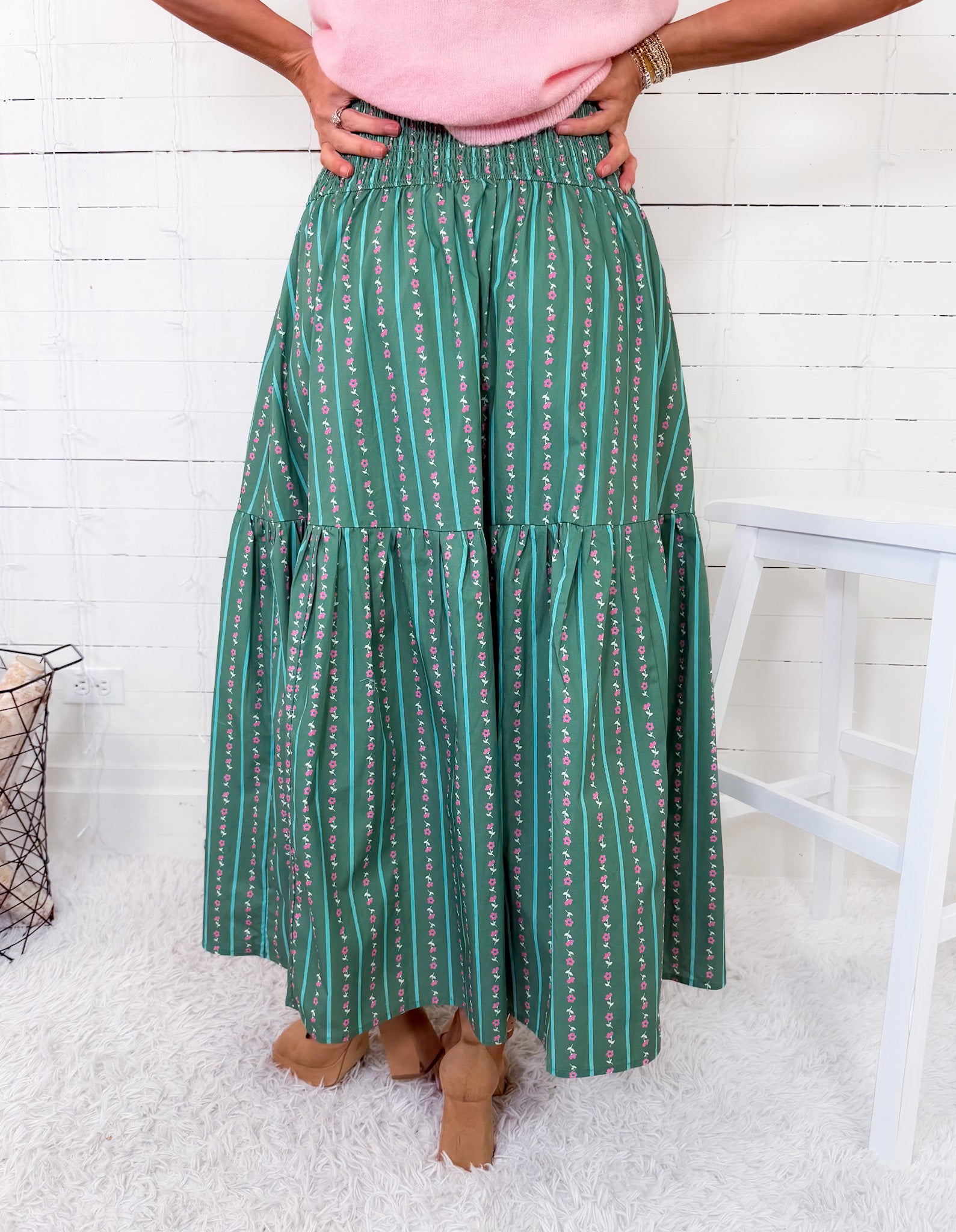 Person wearing a green patterned skirt with a white wooden floor background