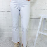 Person wearing light blue jeans with a pink sweater and white sneakers in a minimalistic setting.