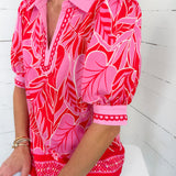 Person wearing a red and pink floral patterned shirt against a white background