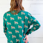 Person wearing a teal sweater with animal pattern against a white wooden background