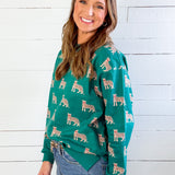 Woman wearing a green sweater with animal patterns against a white wooden wall.