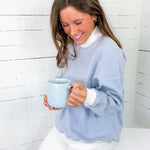 Woman holding a blue mug against a white wooden background
