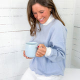 Woman holding a blue mug against a white wooden background