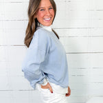 Woman wearing a blue striped sweater over a white shirt against a white wooden panel background
