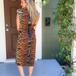 Woman wearing a tiger-striped dress standing on a porch.