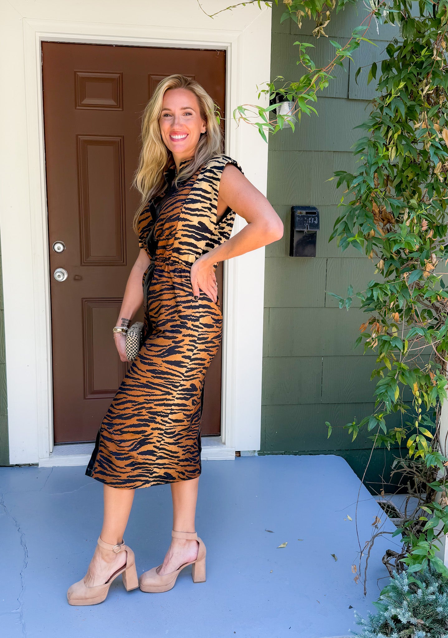 Woman in a tiger print dress standing on a porch