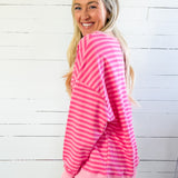 Woman wearing a pink and white striped outfit against a white wooden panel background