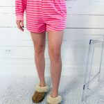 Person wearing pink striped pajama set with brown slippers on a white background
