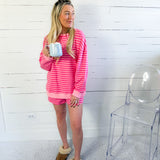 Woman in pink striped loungewear holding a mug in a room with a white wall and clear chair.