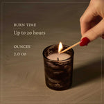 Candle being lit with text about burn time and size on a wooden surface