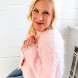 Woman wearing a pink fluffy jacket against a white wooden panel background