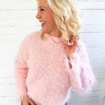 Woman wearing a pink fluffy sweater against a white wooden panel background