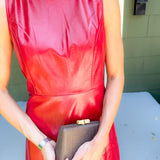Person wearing a red dress holding a clutch in an outdoor setting