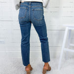 Person wearing blue jeans and brown shoes in a minimalistic setting