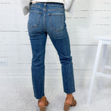 Person wearing blue jeans and brown shoes in a minimalistic setting