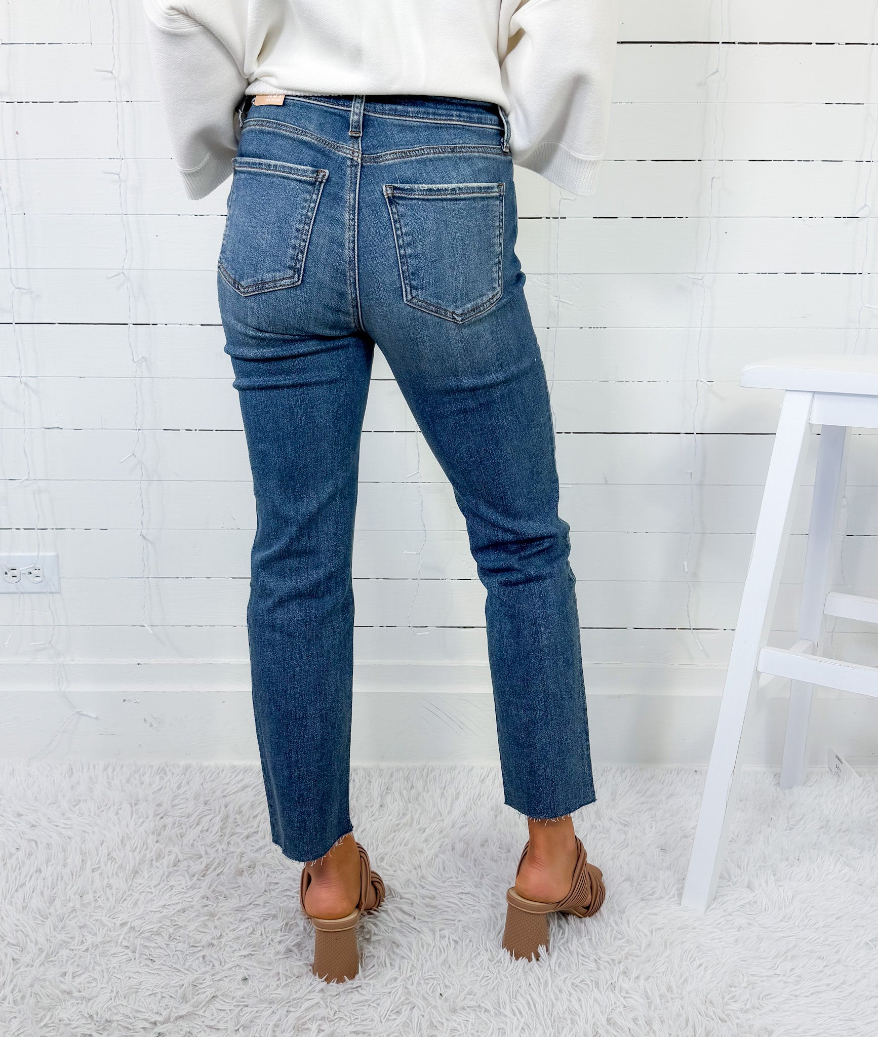 Person wearing blue jeans and brown shoes in a minimalistic setting