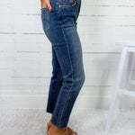 Person wearing blue jeans and a white sweater against a white wooden panel background